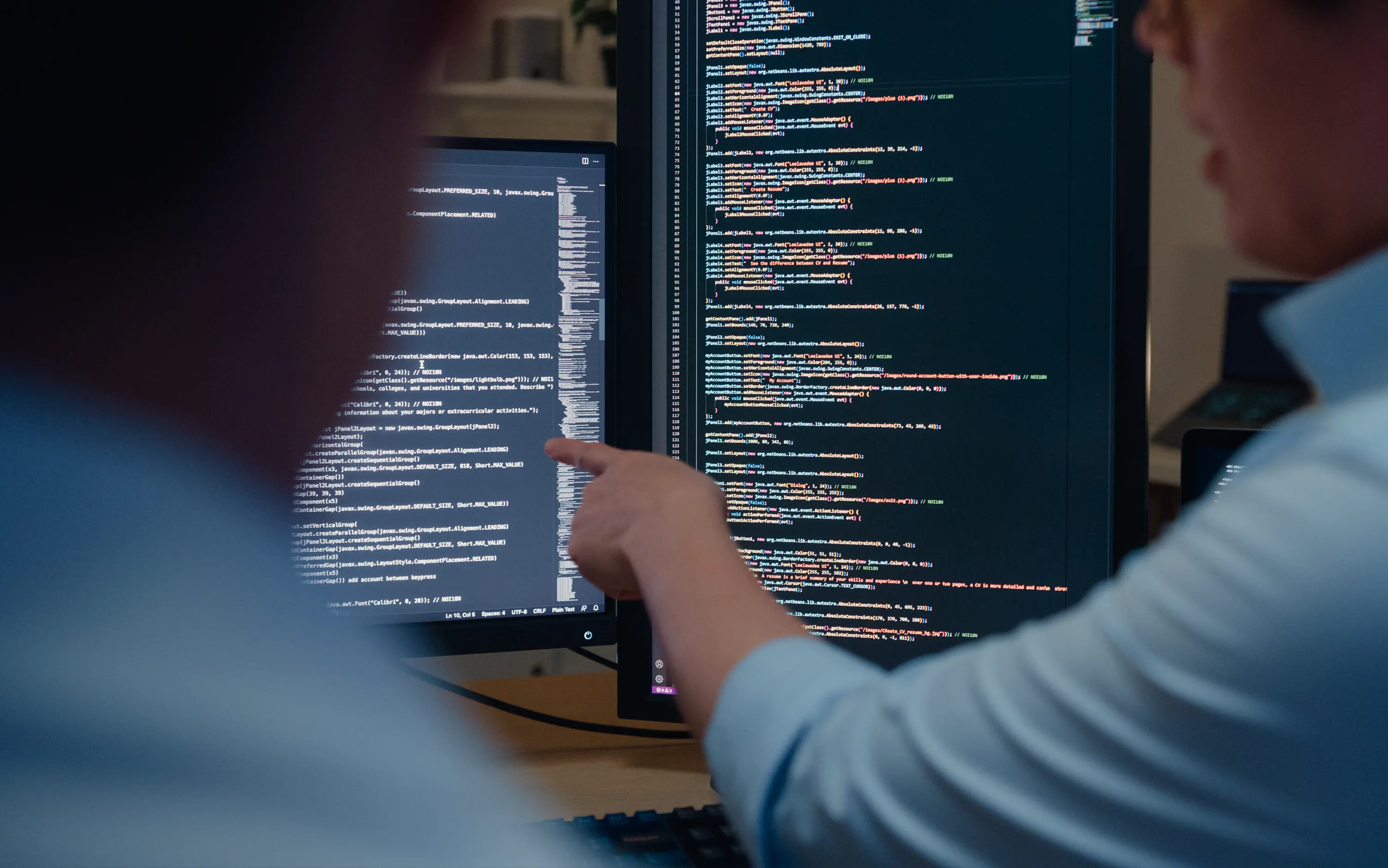 A person holds a hand in front of a screen displaying lines of code.